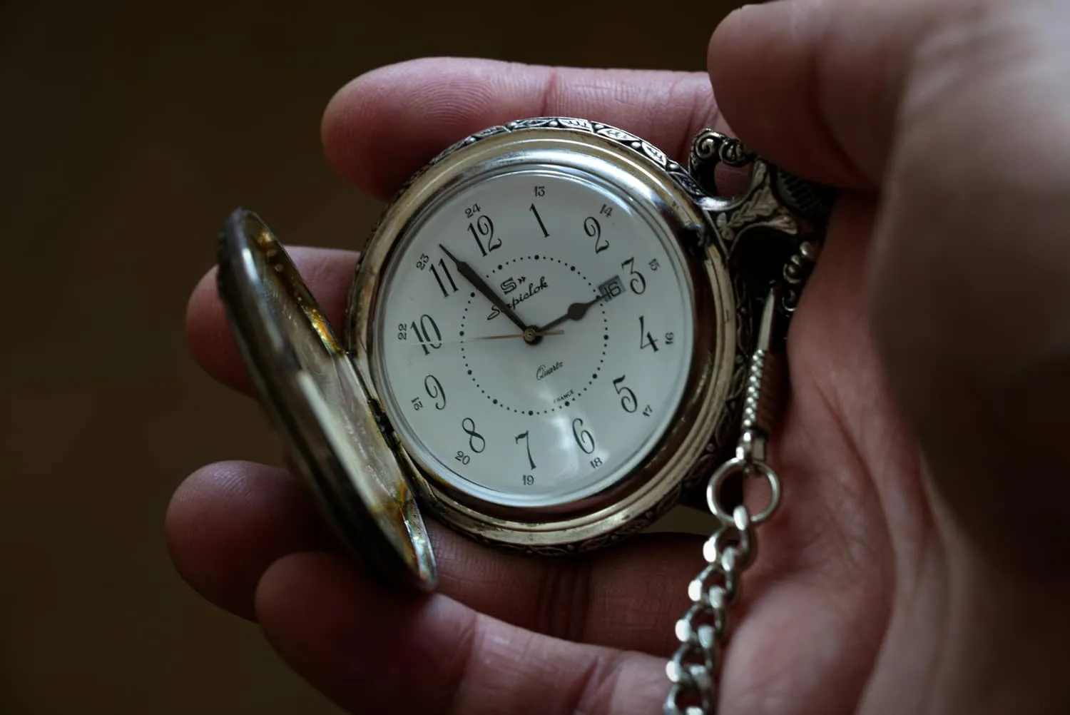 An open pocket watch resting in an open hand — the reporting clocks that start before a company knows the scope of an incident.