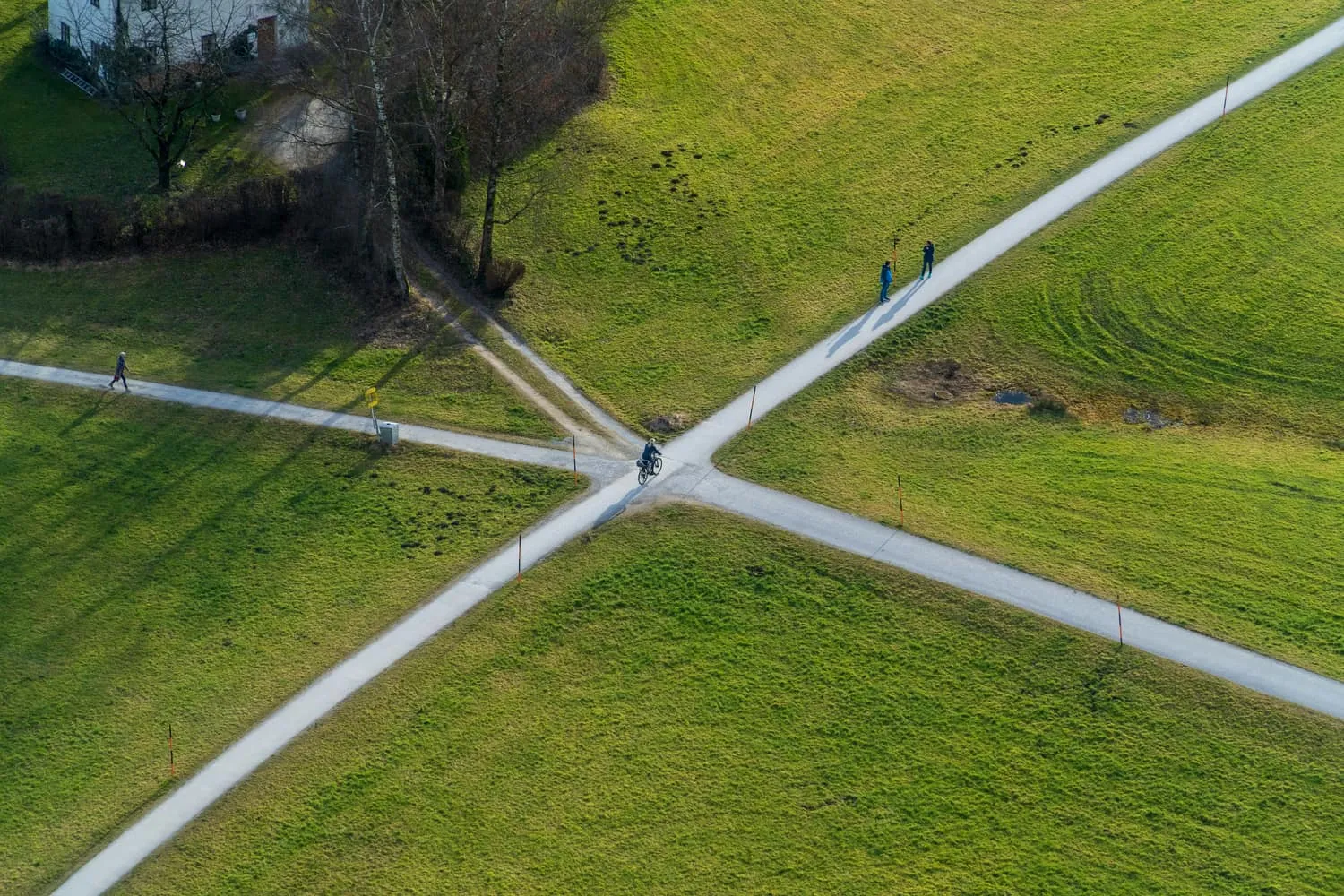 An aerial view of two paths crossing in a green field, a cyclist pausing at the intersection — which regulatory route applies to you.