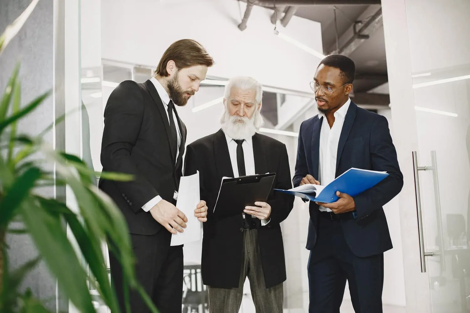 Three professionals in an office comparing documents held in separate folders — the three-way choice this guide is about.